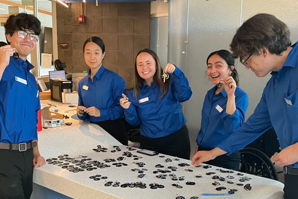 Five CDAs in blue uniform shirts, organizing keys at a front desk.